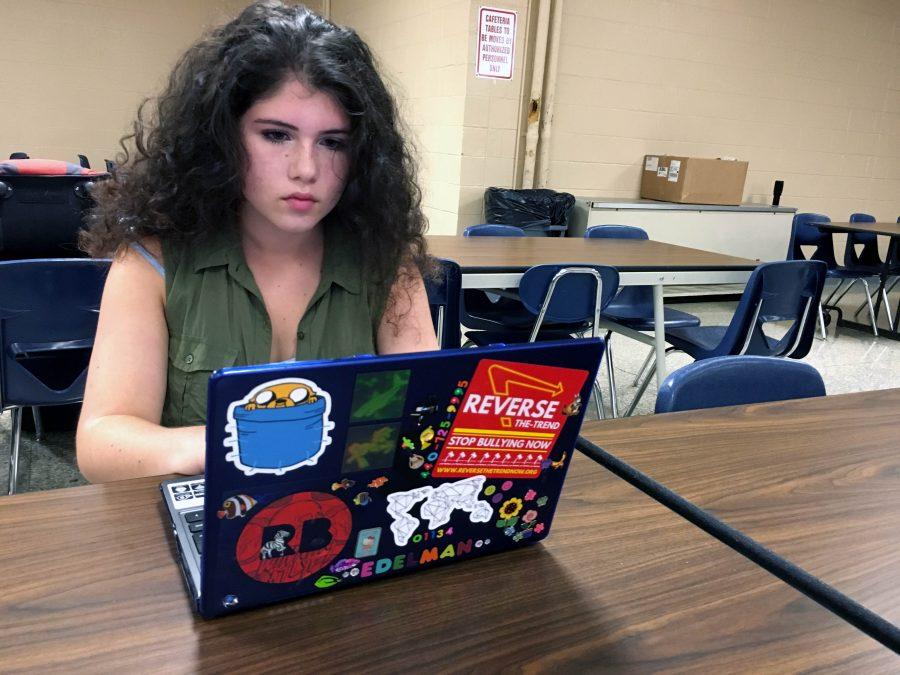 Sophomore Laila Edelman uses her Chromebook, decorated with stickers, before school in the cafeteria.