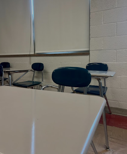 Desks sit empty in a classroom with absent students. 