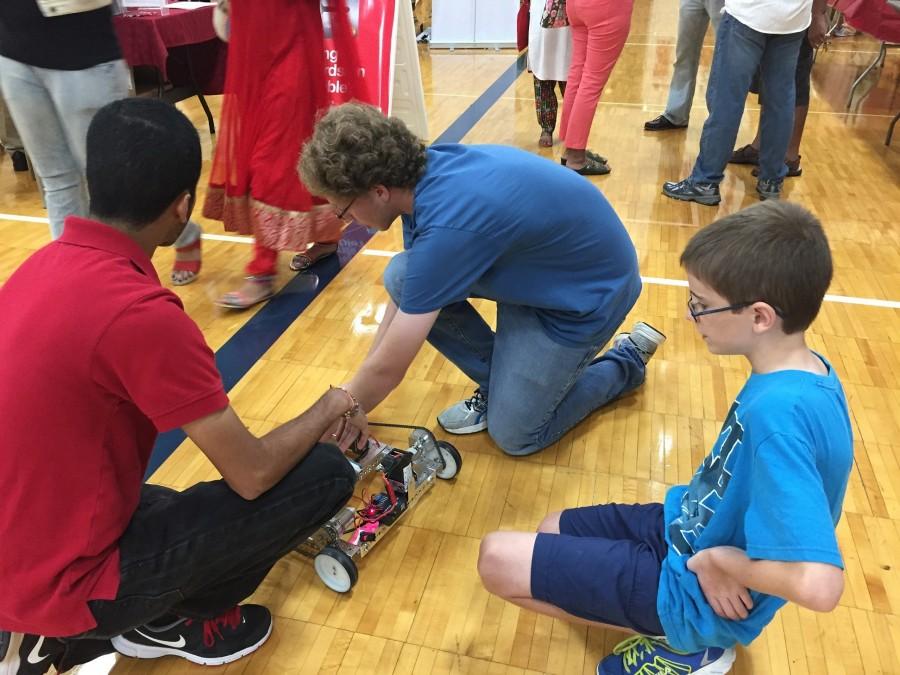 Addison Tisch (center) and Akshay Jain (left) fix their robot  in front of spectators at the India Fest at Independence High School on Sept. 12.