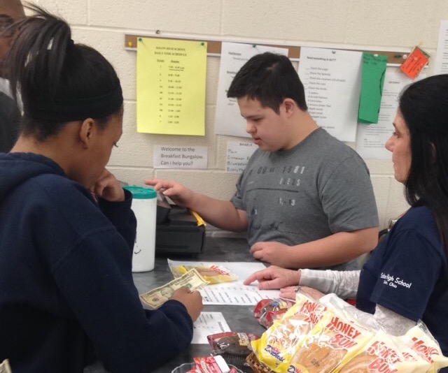 SHS interventionist Elizabeth Jedinak watches her student work with customers at the Bungalow Café.