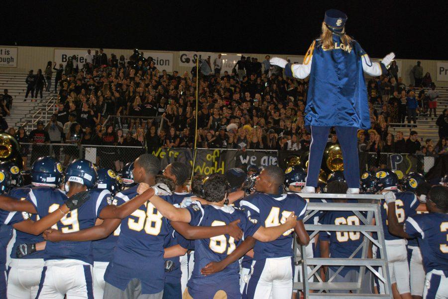 Laura Mayer directs the band while fans lock arms to sing the alma mater.
