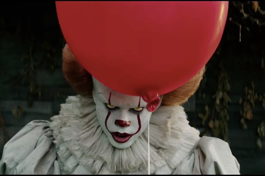 Pennywise (Bill Skarsgård) staring into the camera behind his signature red balloon. 