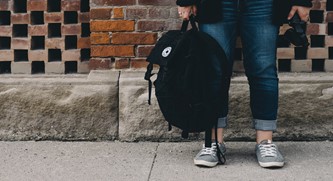 A teen girl stands outside with her backpack. Photo courtesy of unsplash.com