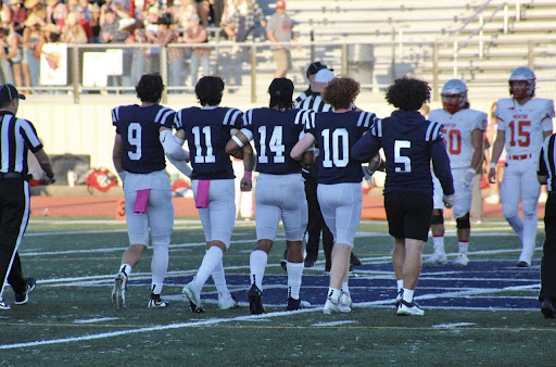 Captains Harley Barmen, Owen Grossman, Max Thompson, Brian McQuaide and Shae Springer walking arm in arm on the field.