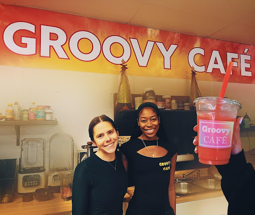 Savannah Allen and Lauren Fellows (left to right) are pictured in front of their café’s name, Groovy Café. Next to Savannah is her favorite menu item- the Tropical Groove smoothie. Fellows actually came up with that smoothie herself, so it “has a special place in [her] heart.” Fellows’s favorite food item is the Chicken Bacon wrap, with breaded chicken. Allen’s favorite smoothie is the Green Goddess: “People can be afraid of greens, but that one surprises you with the taste. It’s nice and sweet, and you’re also getting your greens in for the day.” Her favorite food item is the Veggie Wrap.